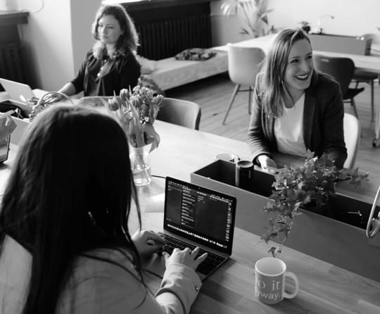 purple filtered image with some women working and one of them is laughing